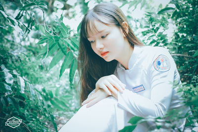 Young woman standing against tree