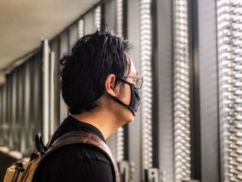 Rear view of young man looking out at window.