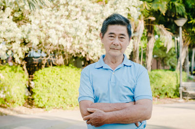 Portrait of senior man standing against trees