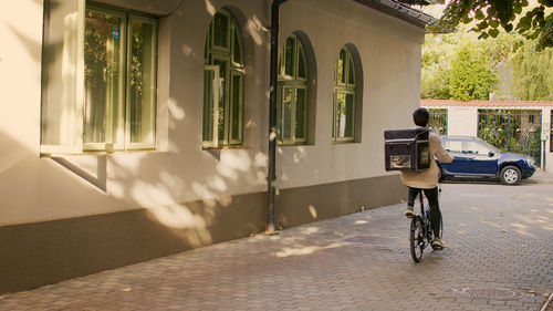 Rear view of man riding bicycle on street