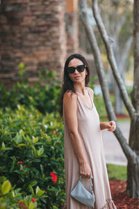 Young woman wearing sunglasses while standing against trees