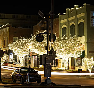 Cars on city street by buildings at night