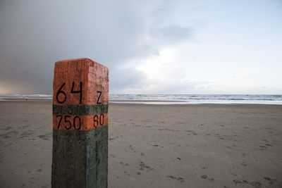 Information sign on beach against sky