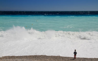 Rear view of boy standing on shore at beach