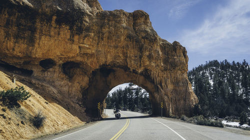 Road leading towards rock formation against sky