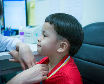 Cropped hand of doctor examining boy at clinic