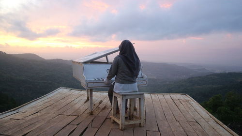 Rear view of woman looking at mountain during sunset