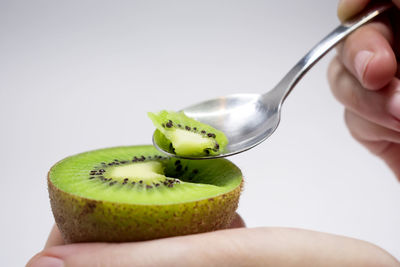 Close-up of hand holding apple against white background