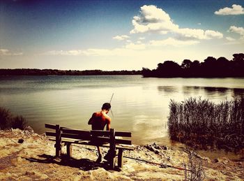 People sitting on bench by lake