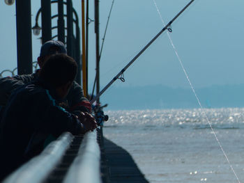 People fishing in sea against sky