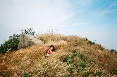 Woman in tall grass against sky