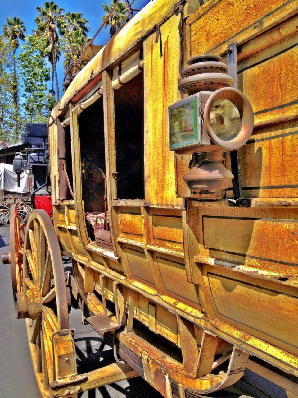 building exterior, architecture, built structure, transportation, mode of transport, land vehicle, day, outdoors, car, reflection, circle, sunlight, old-fashioned, wood - material, tree, stationary, city, street, window, house