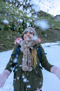 Portrait of young woman standing against trees