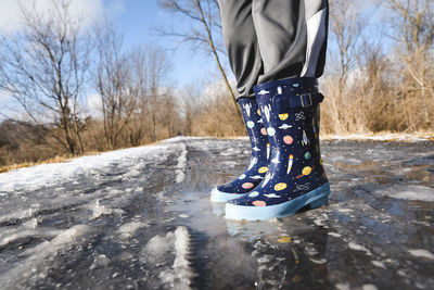 Cropped close up of rubber boots on a slushy trail in winter.