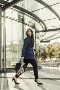 Full length portrait of young woman walking in bus