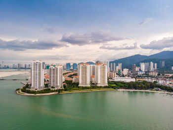 Modern buildings by sea against sky in city