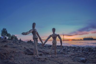 Close-up of sculpture on field against sky at sunset