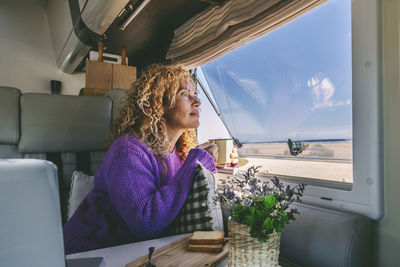 Portrait of young woman looking through window