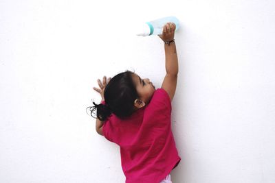 Girl with arms raised against white wall