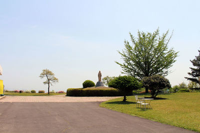 Statue by palm trees against clear sky