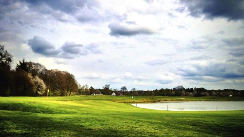 Scenic view of grassy field against cloudy sky