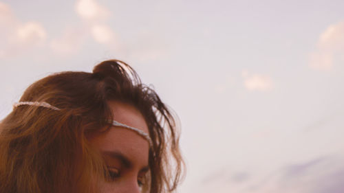 Close-up of young woman against sky during sunset