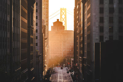 Street amidst buildings in city against sky during sunset