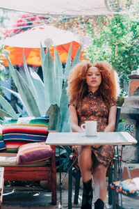 Woman having drink while sitting at cafe