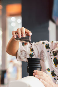 Barista pouring coffee beans into coffee machine tank for grinding in vertical.