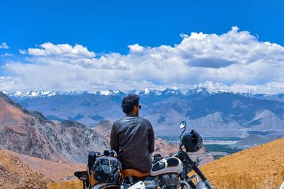 Rear view of man sitting on motorcycle against sky