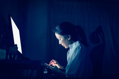 Side view of young woman using mobile phone