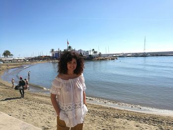 Woman standing on beach by sea against sky