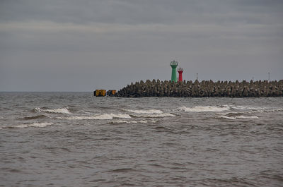 Lighthouse by sea against sky