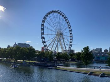 Ferris wheel by river against sky