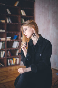 Thoughtful young woman holding paintbrush