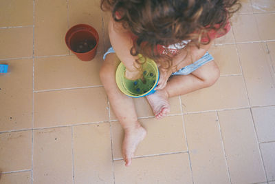 High angle view of girl playing on tiled floor