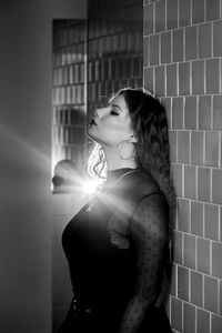 Portrait of young woman standing against wall