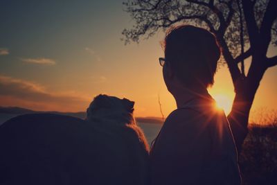 Rear view of silhouette woman against sky during sunset