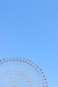 Low angle view of ferris wheel against clear blue sky