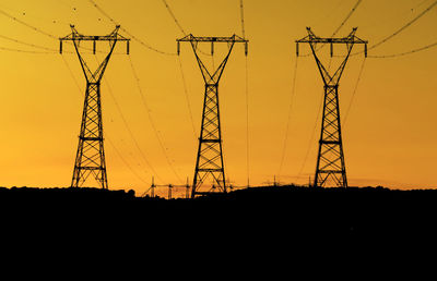 Low angle view of silhouette electricity pylon against sky