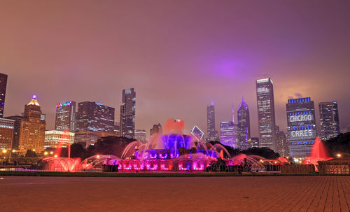 Illuminated buildings in city against sky at night