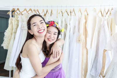 Portrait of happy woman embracing friend in bridal shop