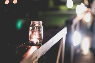 Burning tea light candle on railing at night