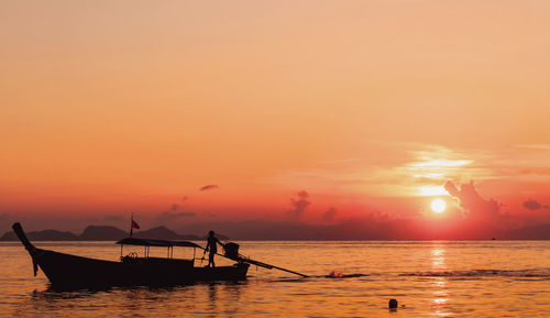 Silhouette boat in sea against orange sky