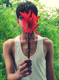 Portrait of young man standing by flowering plants