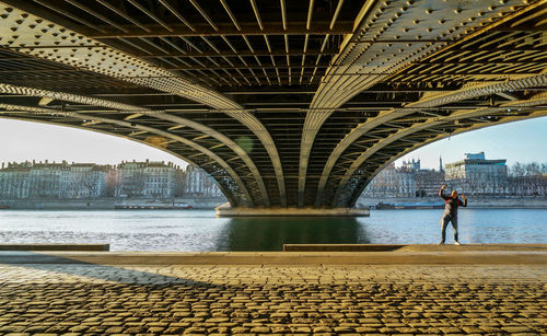 Man on bridge over river in city against sky