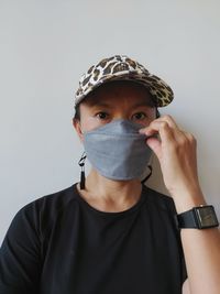 Portrait of young man covering face against white background