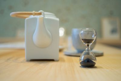 Close-up of hourglass by kettle on table