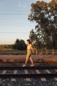 Man sitting on railroad track against sky