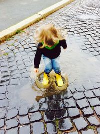 Full length of girl playing in puddle on sidewalk
